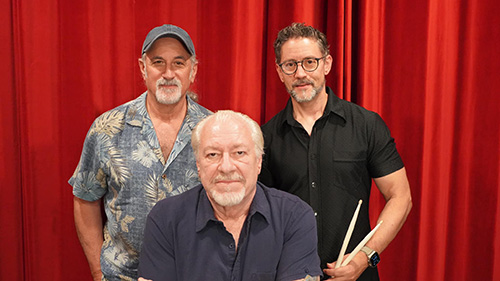 members mosaic groove trio photo standing in front of a red curtain, with one seated in the middle.